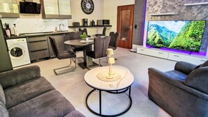 Un salon moderne comprenant un coin repas, un téléviseur à écran plat et un lave-linge.