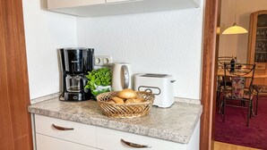 Une cuisine équipée d’une machine à café, d’un grille-pain et d’un panier en osier contenant du pain.