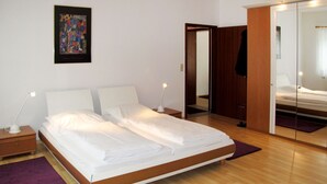 Une chambre moderne avec un grand lit, des tables de chevet avec des lampes, un plancher en bois et un miroir.