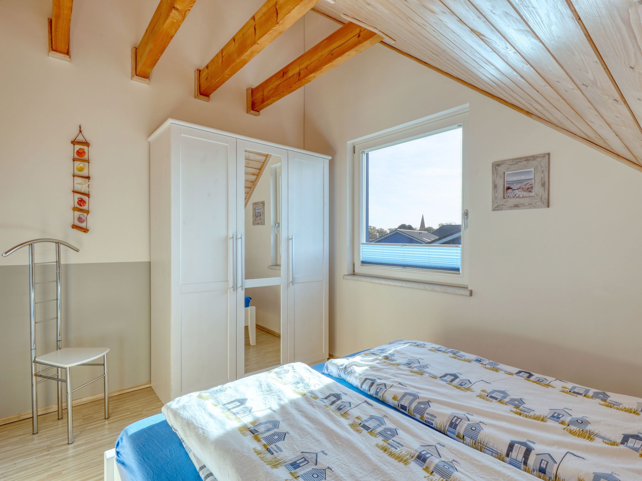 A bedroom with a bed, a window with a view, a wardrobe, and a ladder.