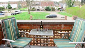 A patio with two striped chairs, a table, and a bottle of wine. - Am Park by Interhome (Raben Steinfeld)