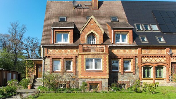 A large brick house with a central entrance, multiple windows, and a chimney. - Am Park by Interhome (Raben Steinfeld)