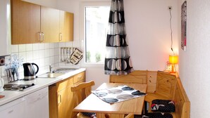 A compact kitchen with wooden cabinets, a sink, and a dining table with chairs. - Waldhäuser by Interhome (Himmelpfort)