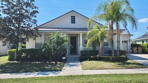A two-story residential house with a front porch, a garage, and a well-maintained lawn. - Spacious 5-bedroom house in delightful Kissimmee with AC, WiFi (Kissimmee)