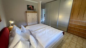 Ein Schlafzimmer mit Bett, Nachttisch, Lampe, Kleiderschrank und einem Bild an der Wand.