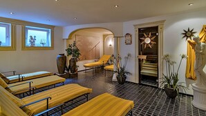 Ein Spa-Raum mit mehreren, gelb gestreiften Massagetischen, einem großen Fenster mit Aussicht und einer Statue einer Frau.