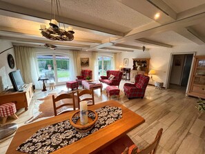 A spacious living area with a dining table, red plaid chairs, and a fireplace.
