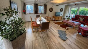 Ein geräumiges Wohnzimmer mit Essbereich, einer Sofagarnitur und einem Fernseher.