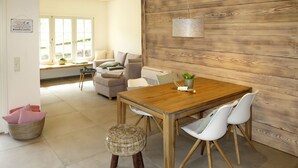A dining area with a wooden table, white chairs, and a hanging light fixture.