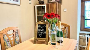 A dining table with a chalkboard sign, a vase of red flowers, and two wine bottles. - Holiday Home am Bostalsee by Interhome (Oberthal)