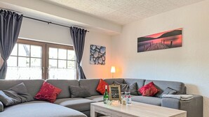 Een moderne woonkamer met een grijze modulaire bank, een houten salontafel en een schilderij aan de muur.