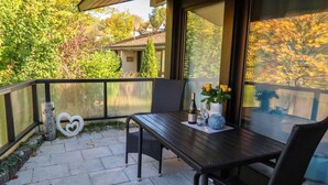 A patio with a table and chairs, a heart-shaped decoration, and a bottle of wine.