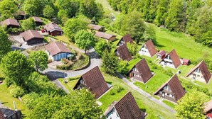 A village with traditional houses, narrow roads, and surrounding greenery.