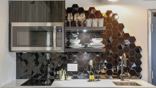 A modern kitchen with a built-in microwave, a stainless steel sink, and a hexagonal tile backsplash.