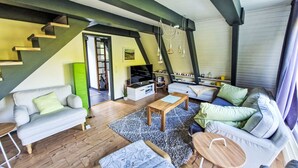 A modern living room with a staircase, a sofa, a coffee table, and a TV. - Winnetou by Interhome (Ronshausen)