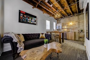 A living room with a dark leather sofa, a wooden coffee table, and a mounted Netflix screen. - Westlake Hotel - The Noire Suite (Etobicoke)