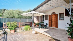 A patio with a table and chairs, surrounded by potted plants and a wooden fence. - Gorgeous apartment in Piano di Mommio (Piano di Mommio)