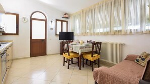 A cozy kitchen with a dining table set for four, a sofa, and a TV mounted on the wall. - Gorgeous apartment in Piano di Mommio (Piano di Mommio)