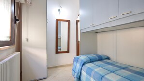 A bedroom with a bed, a radiator, a mirror, and a wardrobe. - Gorgeous apartment in Piano di Mommio (Piano di Mommio)