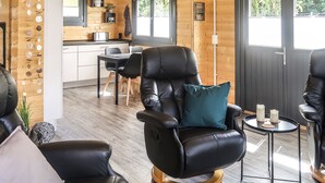 Una habitació acollidora amb un butac armchair de cuir, una taula rodona petita amb espelmes, i un terra de fusta.