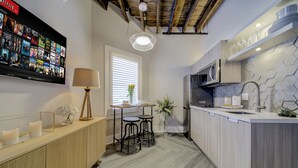 Une cuisine moderne dotée d’un téléviseur encastré diffusant un service de streaming, d’un coin bar en bois et d’un pare-feu avec un motif hexagonal.