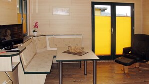 Een knus woongedeelte met een kitchenette, een bank, een eettafel en een zwarte stoel.
