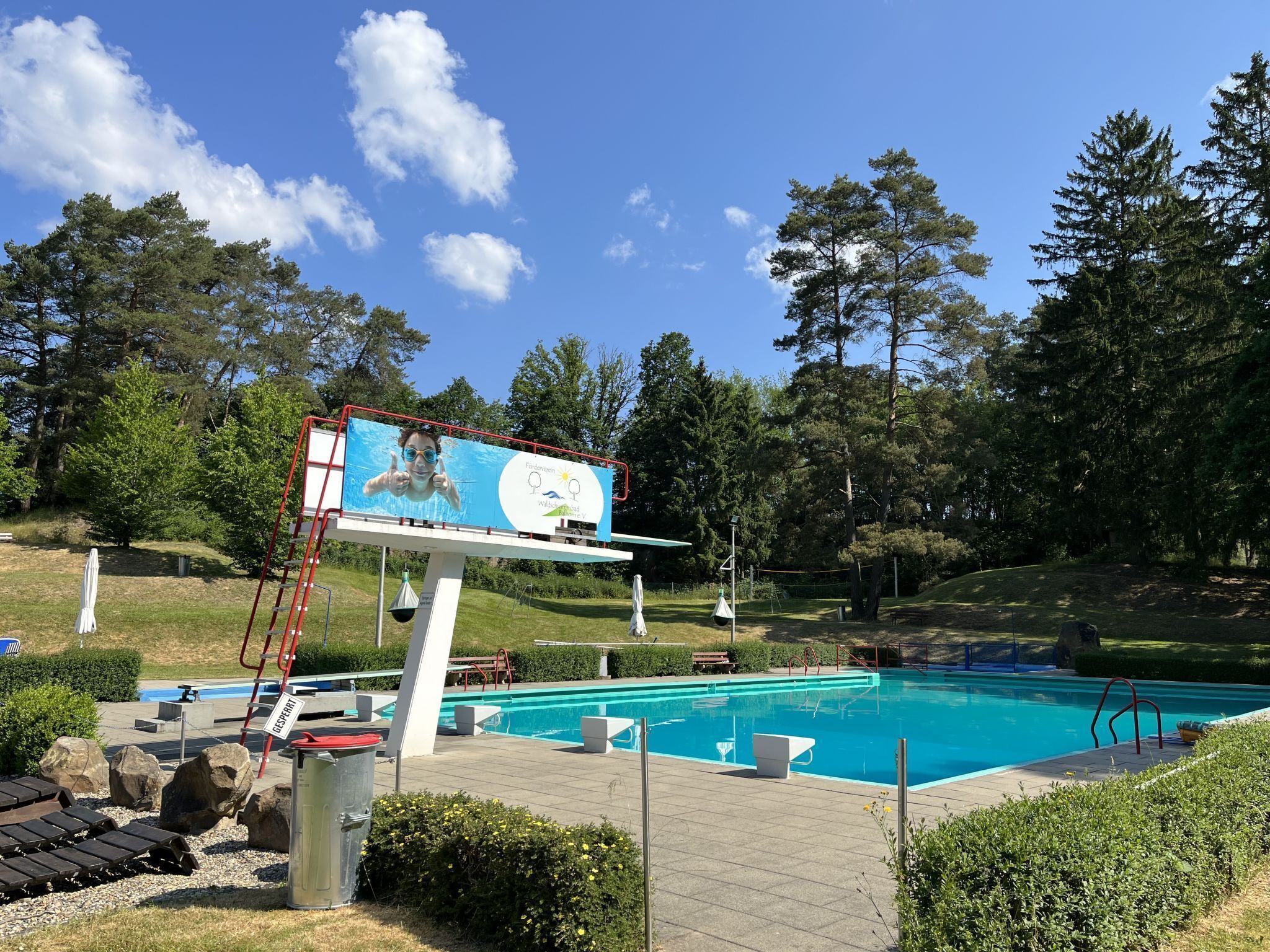 Una piscina con tablon y puesto de salvavidas.