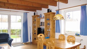 A dining area with a wooden table and chairs, a television, and a bookshelf. - Kitowski by Interhome (Hooksiel)