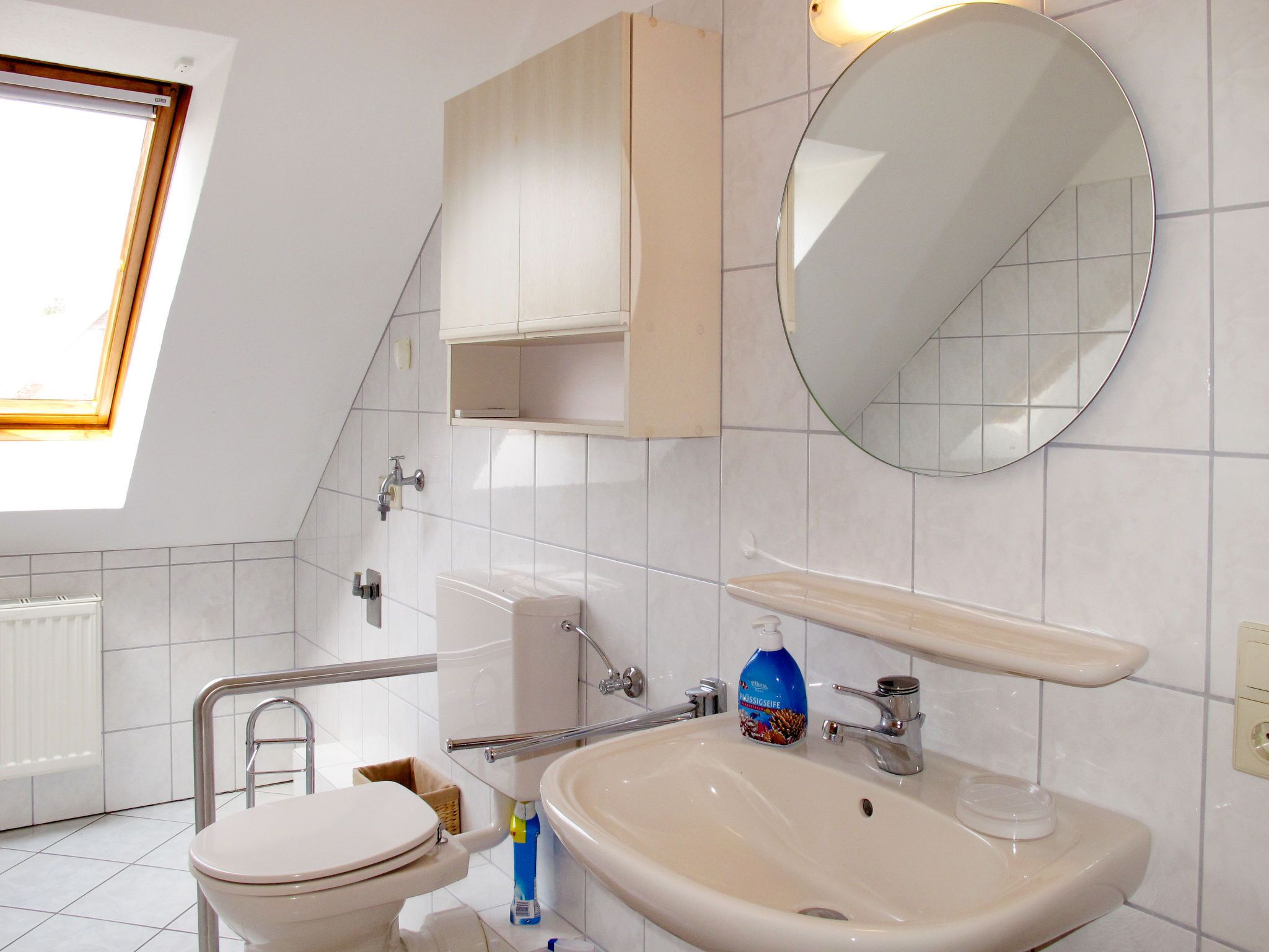 Une salle de bain moderne équipée de toilettes, d’un lavabo, d’un miroir et d’une fenêtre.