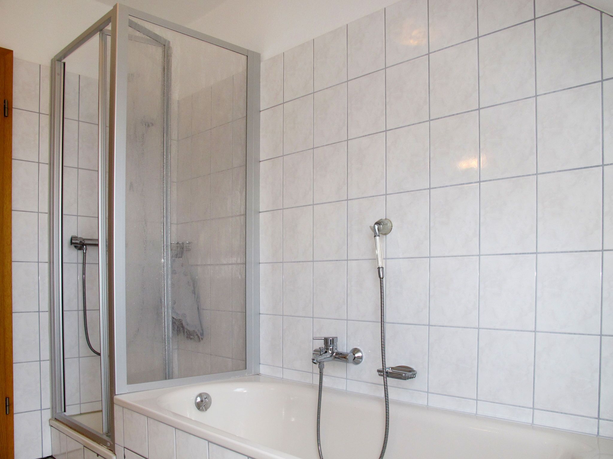 Une salle de bain avec une douche à parois de verre, une baignoire et des murs carrelés.