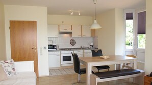 Una cocina compacta con comedor, una puerta de madera y un ventanal con persianas.