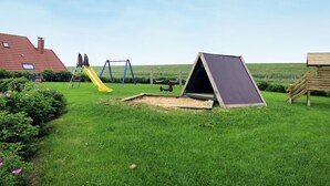 Un parque infantil con tobogán, columpios y una estructura para escalar.