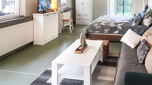 Un dormitorio compacto con cama, un pequeño escritorio, una silla y televisión.