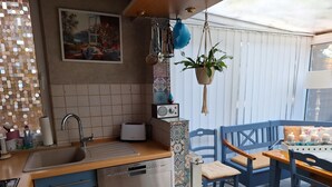 Cocina compacta con lavavajillas, tostadora y una planta colgante.