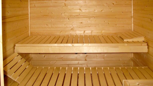 Una sauna con bancos de madera y suelo de tablones.