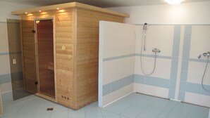 Un baño con sauna de madera, zona de ducha y paredes de azulejos.