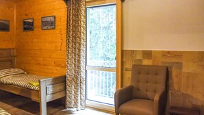 Habitació d'una cabana acollidora, amb un llit, una cadira i una finestra amb cortines.