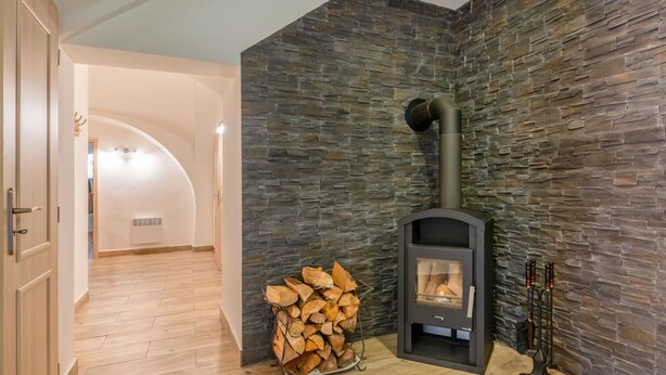 A modern interior with a stone wall, a wood-burning stove, and a stack of firewood. - Pool & Wellness Estate by Interhome (Destne v Orlickych Horach)