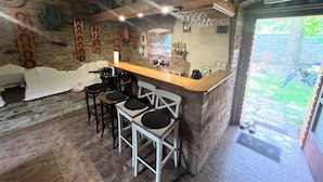 Un rincón de bar acogedor con pared de piedra, mostrador de madera y taburetes.