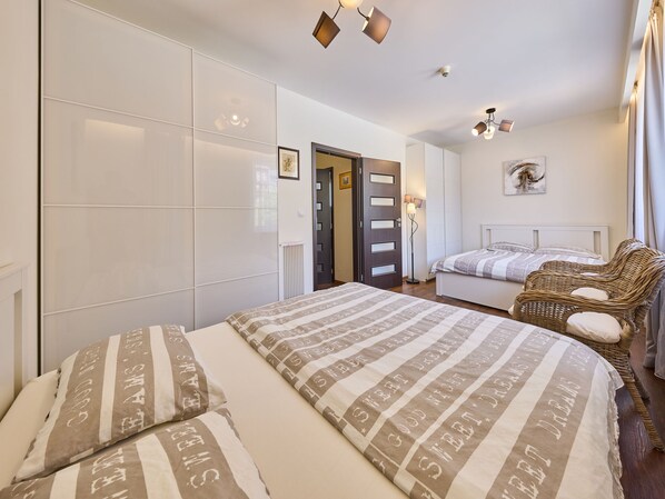 A bedroom with a bed, a wicker chair, and a wardrobe.