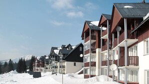 Une rangée d’immeubles modernes à plusieurs étages, dotés de balcons, se dressant sur fond de montagnes enneigées.