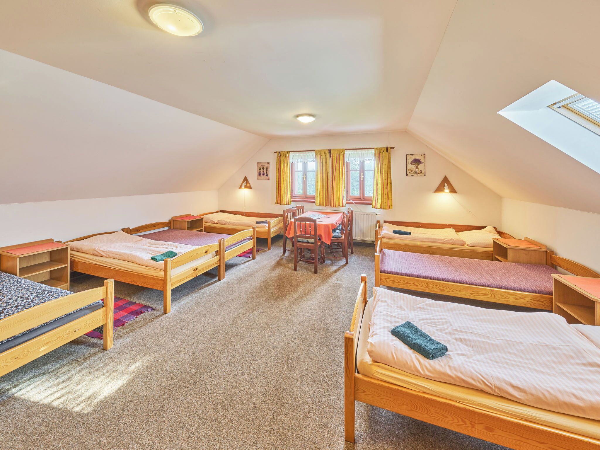 Una camera del dormitorio con quattro letti in legno, un tavolo da pranzo, sedie e una finestra con tende.