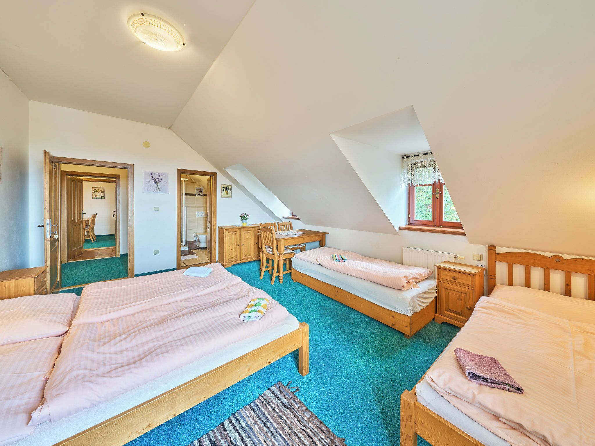 A bedroom with two beds, a desk, and a chair.