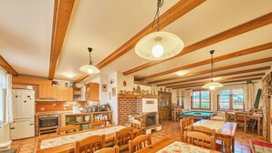 A cozy, well-lit room with wooden beams, a pool table, and a fireplace.