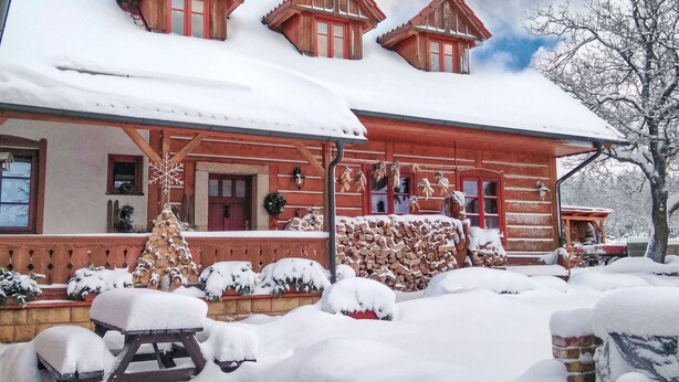 A wooden chalet with a snow-covered roof and a front porch.