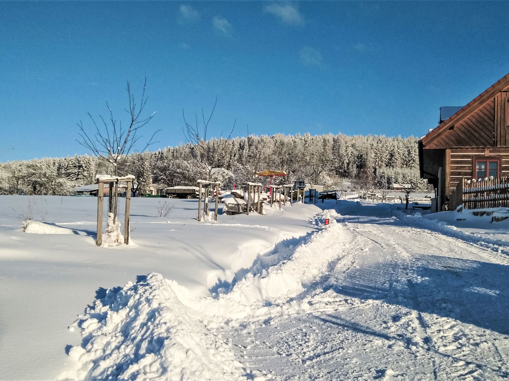 Schneebedeckte Landschaft mit einer Holzhütte und blauem Himmel.