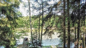 A forested area with a stone structure near a body of water, likely a lake or pond. - Lake & Rest by Interhome (Strizovice)