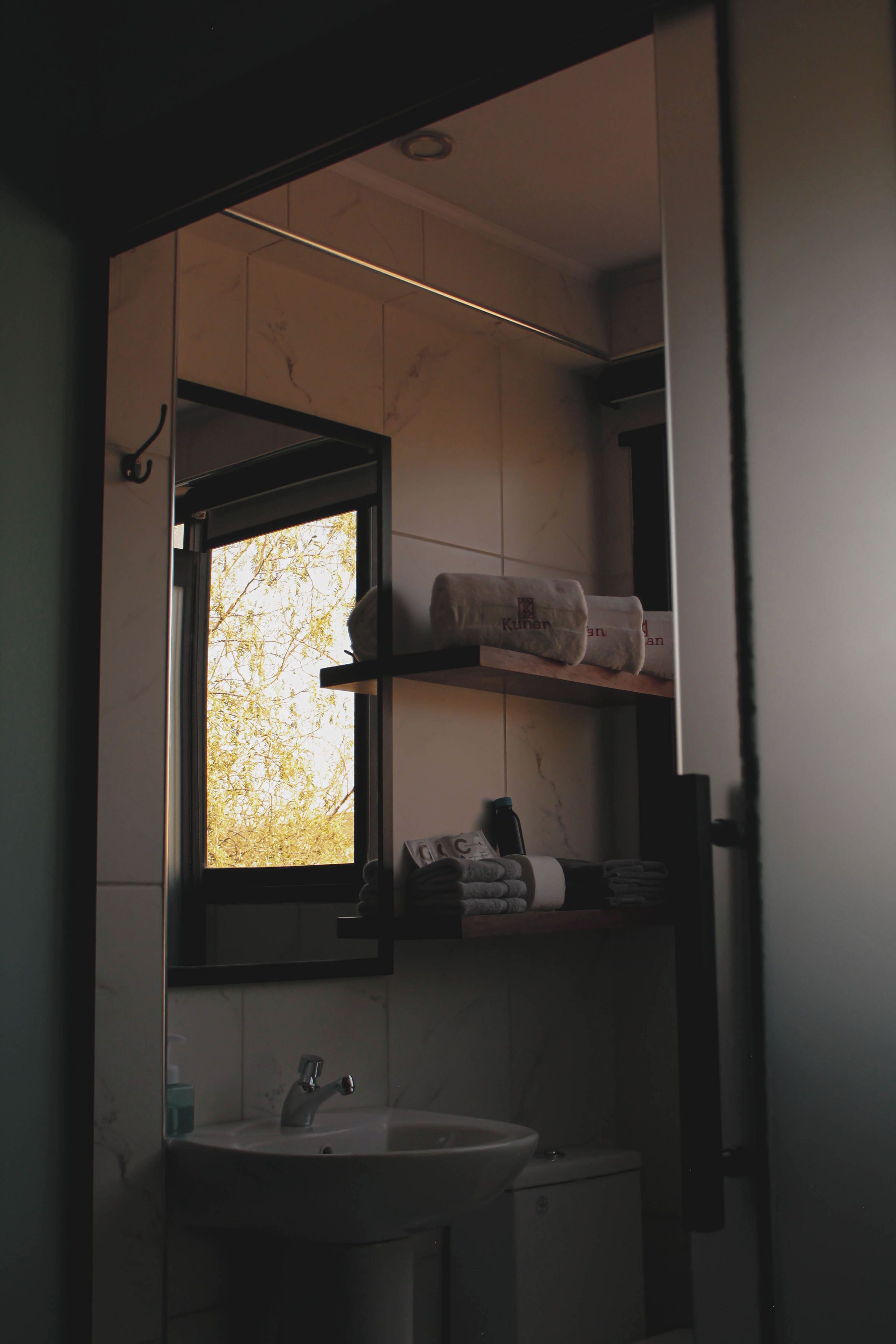 Ein Badezimmer mit Fenster, Waschbecken und Regalen mit Handtüchern.