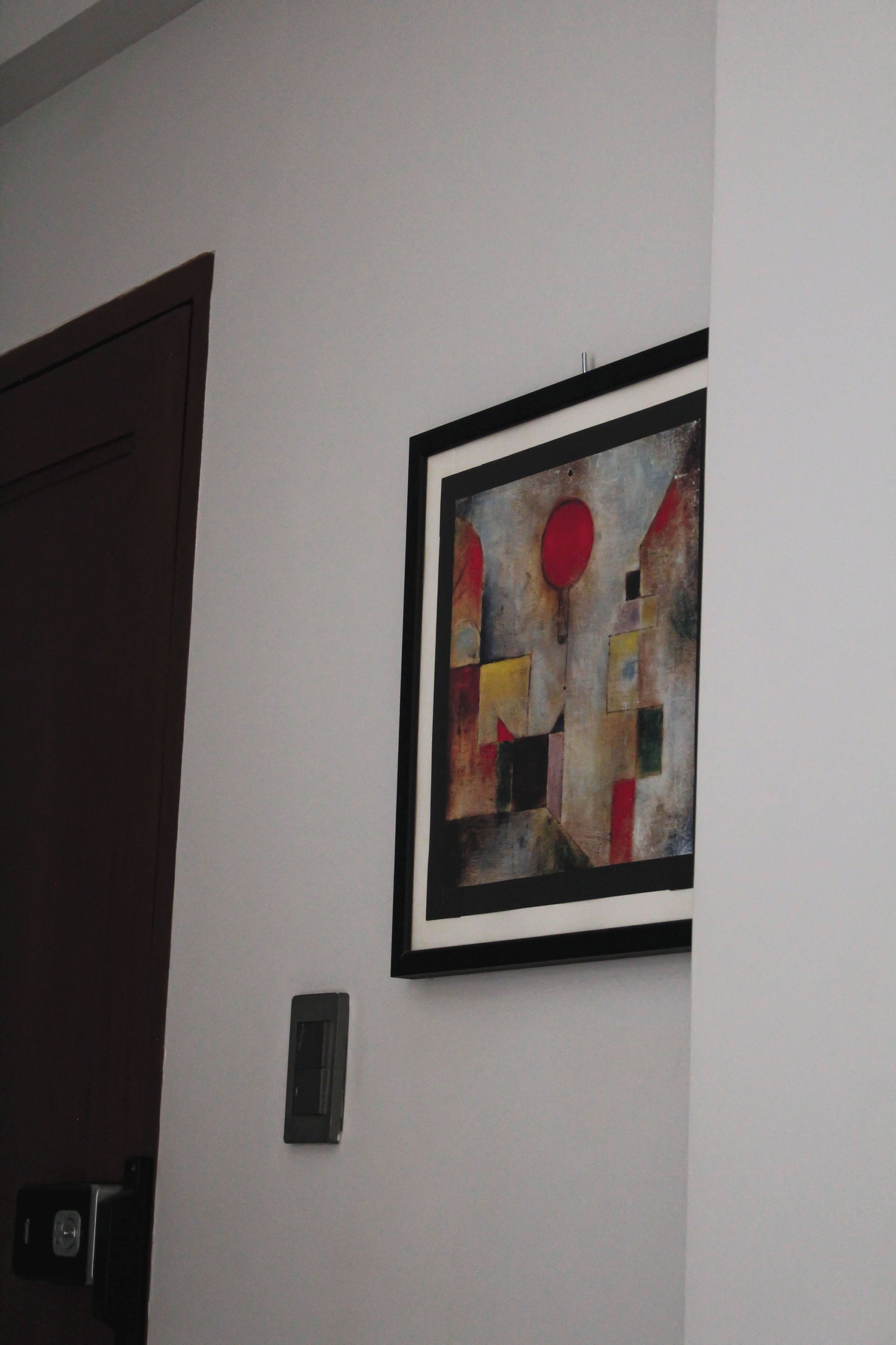 A wall with a framed abstract painting and a door.