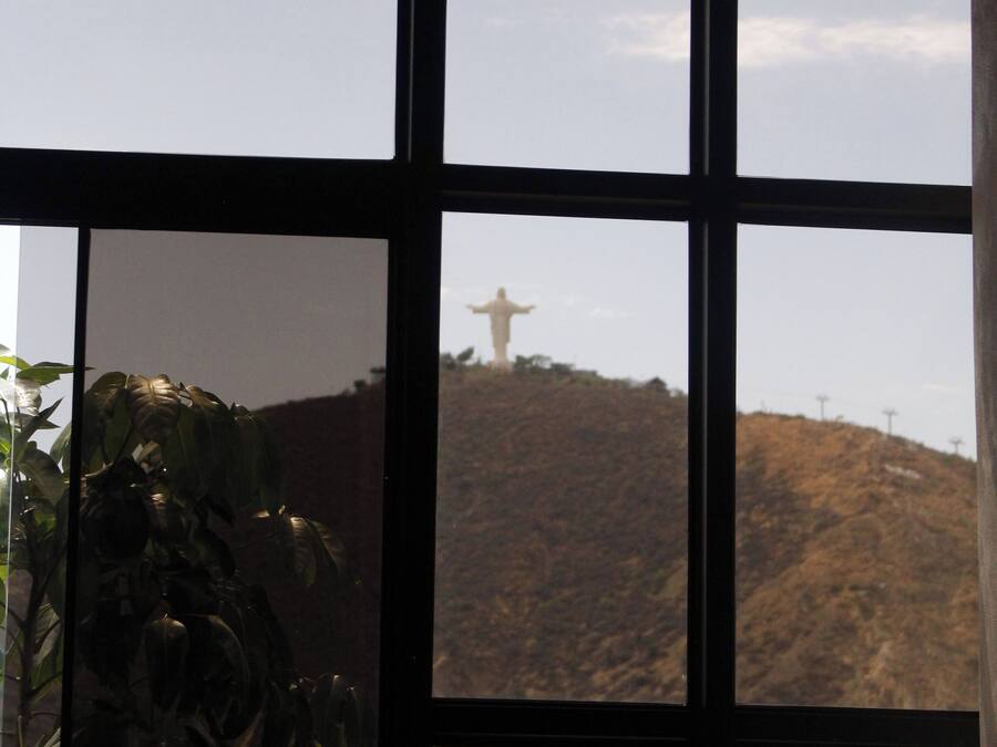 A window with a view of a hill and a statue.